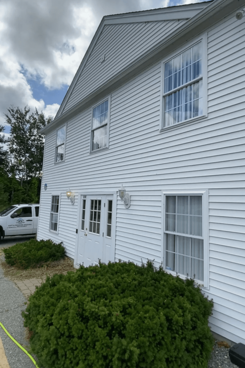 Side view of clean white horizontal vinyl siding on a two-story residential home after a professional soft wash.