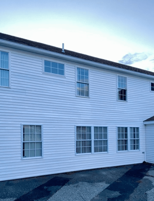 Clean white vinyl siding and windows on a multi-story commercial building exterior following a professional soft wash service.